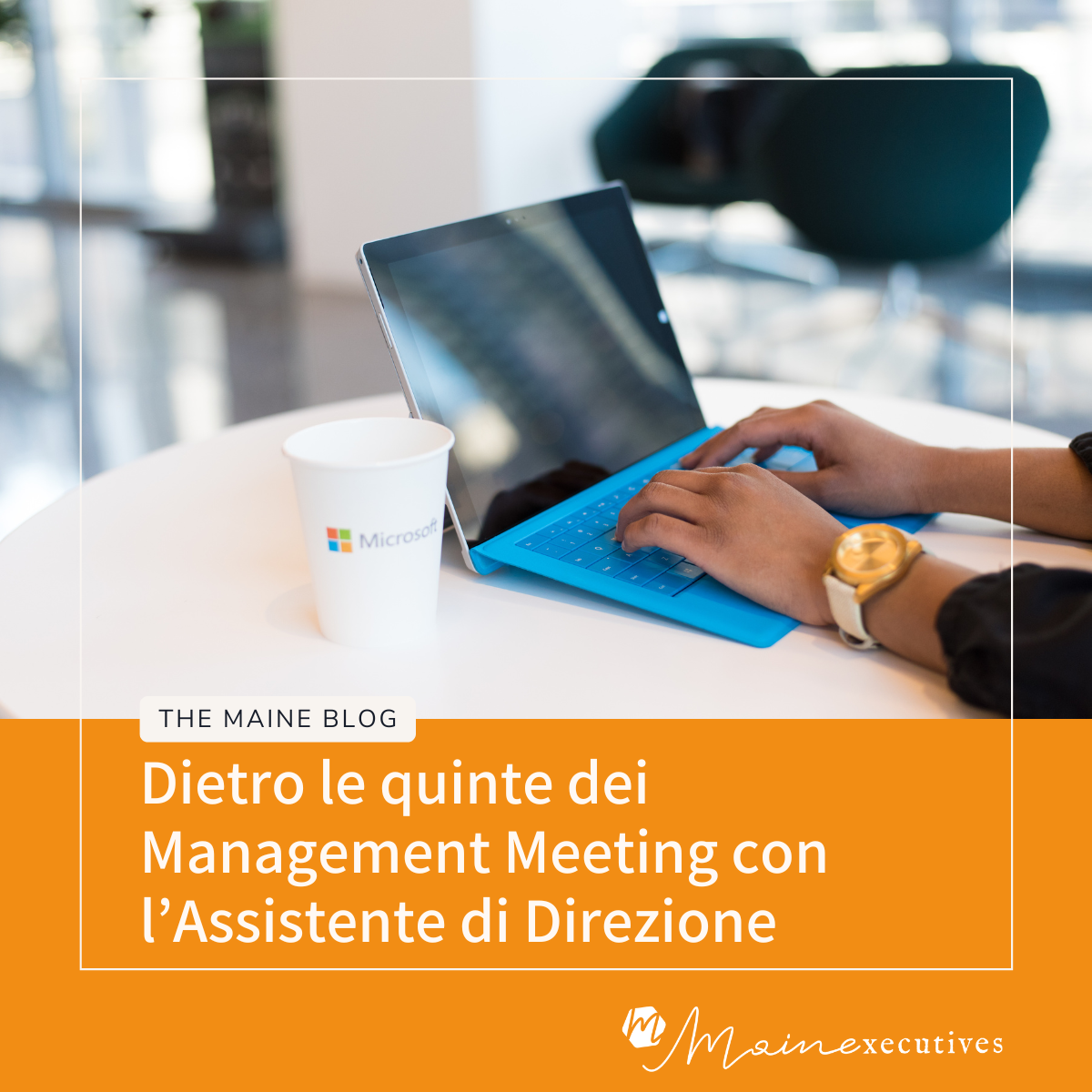 Assistente di Direzione al lavoro su un laptop durante la preparazione di un Management Meeting, con tazza Microsoft su un tavolo bianco moderno