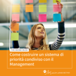 Executive Assistant organizza post-it colorati su una parete di vetro per definire priorità condivise con il Management Executive Assistant organizza post-it colorati su una parete di vetro per definire priorità condivise con il Management
