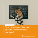 Donna bionda di spalle scrive su una lavagna durante un momento di lavoro e confronto